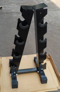 A black metal multi-grip weight bench stand with multiple curved pegs on each side, resting on a cardboard box on a concrete floor.