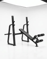 A black adjustable weight bench press with a safety guard and dual roller attachments, photographed in a clean white studio setting.