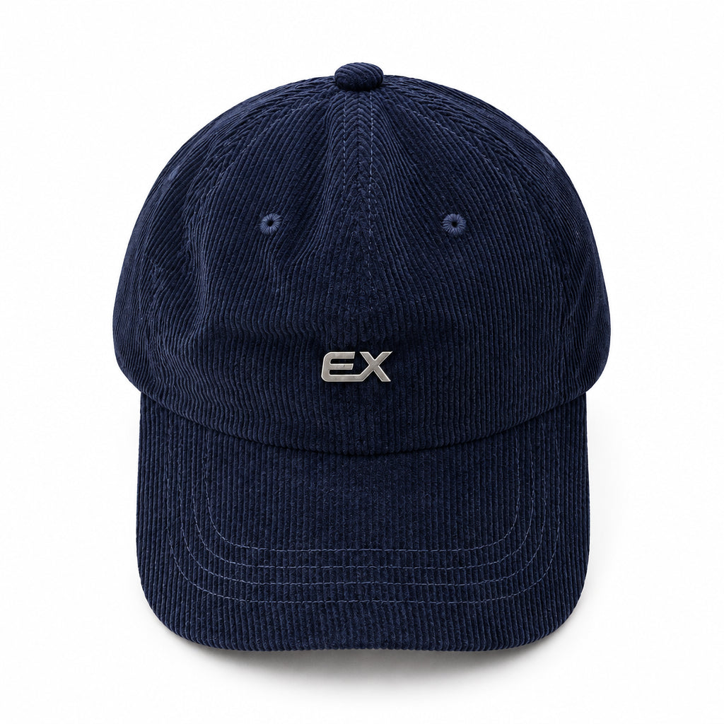 A dark navy blue corduroy baseball cap with a small silver 'EX' logo on the front, displayed on a light beige fabric background.