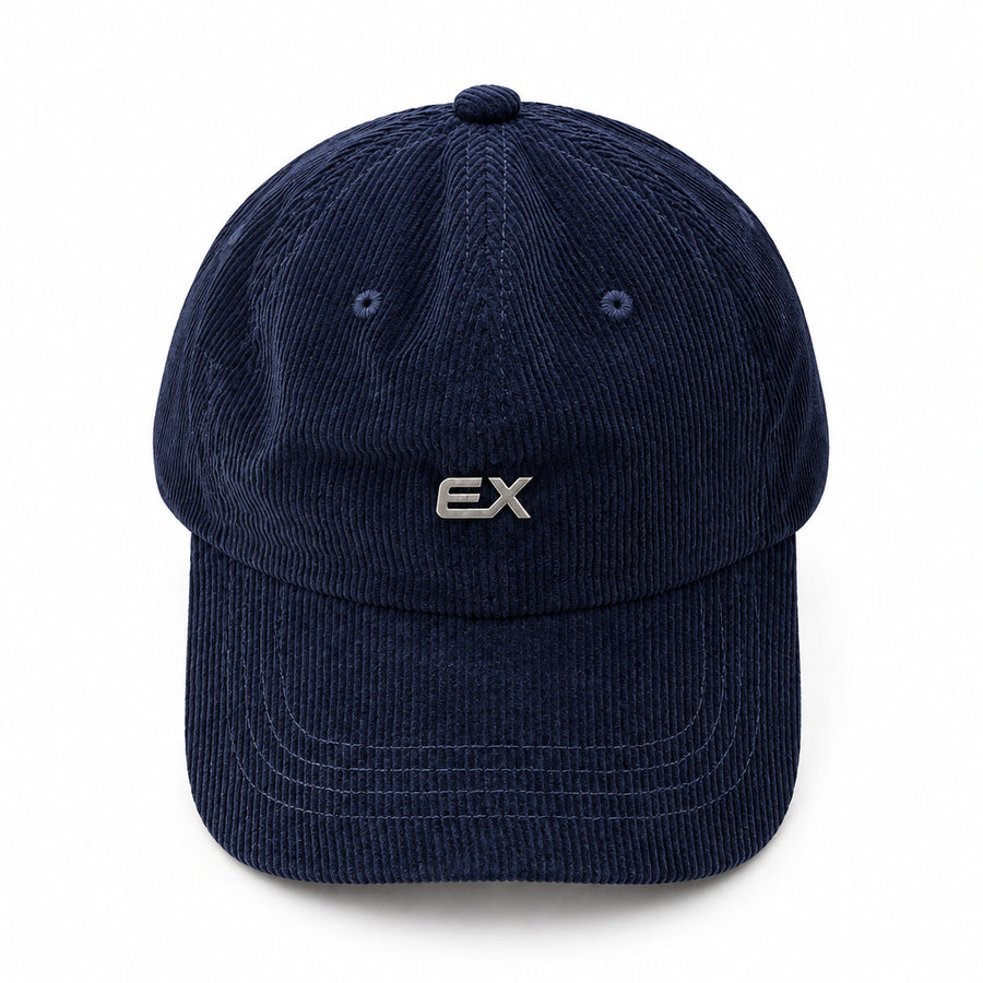 A dark navy blue corduroy baseball cap with a small silver 'EX' logo on the front, displayed on a light beige fabric background.