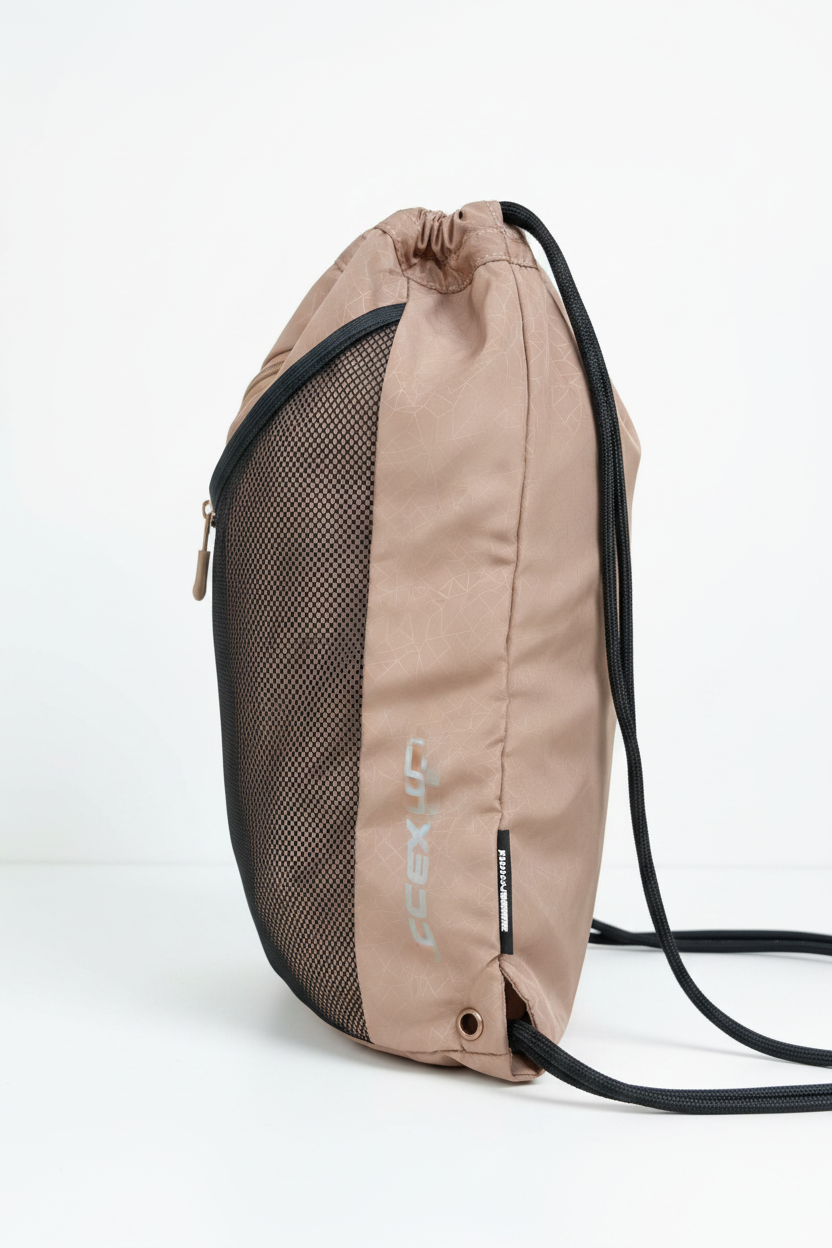 A tan and black drawstring backpack with a mesh front panel and vertical 'SOCCERAX' branding, shown worn over a purple shirt.