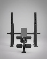 A black adjustable weight bench with a padded backrest, dual adjustable footrests, and a horizontal support bar, shown on a clean light gray studio background.