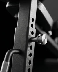 Close-up of a black adjustable weight bench with a silver metal pin and measurement markings in centimeters.